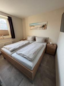 a bedroom with a bed with white sheets and a window at Ferienwohnung-Maxi in Borkum