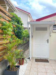 a white garage door on a house with plants at Appartements CHEZ COCO - Résidence de charme au coeur de Terre-de-haut - Clim, kitchenette, terrasse et Wifi - Proche Centre & Plage in Terre-de-Haut