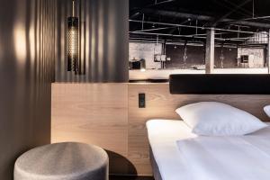 um quarto com uma cama branca e uma cadeira em Four Points Flex by Sheraton Aalborg em Aalborg