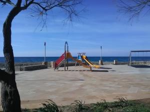玛丽娜迪曼卡维萨A Pochi Metri Dal Mare Seminterrato的海滩上的游乐场,背景是大海