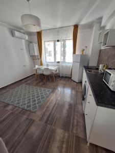 a kitchen with white appliances and a table and a dining room at By the Sea Plusoi Apartment in Năvodari