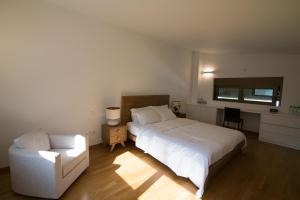 Un dormitorio con una cama blanca y una silla. en Amuse Athens Villa, en Vari 46 fotos más