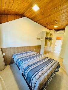 Bett in einem Schlafzimmer mit Holzdecke in der Unterkunft MRG - Convidativa Casa 3D em Condomínio Privativo em Canela - Próximo ao Parque Terra Mágica Florybal in Canela