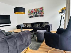 a living room with black leather couches and a table at Tiaré Appartment - FeWo in Bad Harzburg