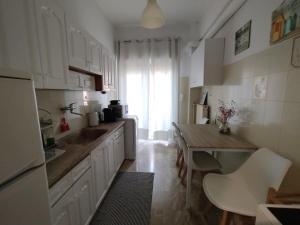 a kitchen with white cabinets and a wooden table at Vasiliki's place in Karditsa