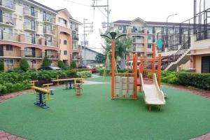 a playground with play equipment on a green field at Cozy 1 Bedroom Unit Arezzo Place Pasig in Pasig