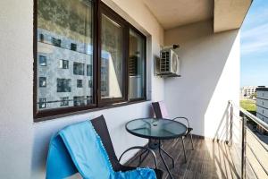 a balcony with a table and chairs and a window at By the Sea Plusoi Apartment in Năvodari +2 photos