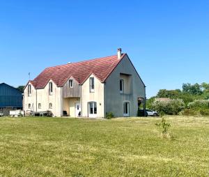 a large white house with a red roof in a field at Gite de l'Ormes Magnolia in Nanteau-sur-Essonnes