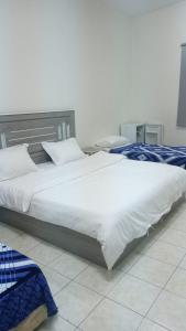 two beds in a bedroom with white sheets and pillows at عمارة المحيسني in Makkah