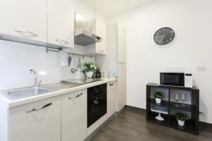 a kitchen with white cabinets and a sink and a microwave at Roma Trastevere Relais Guest House in Rome