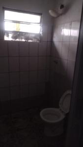 a small bathroom with a toilet and a window at Casa Branca Sobrado in Caraguatatuba +1 photo