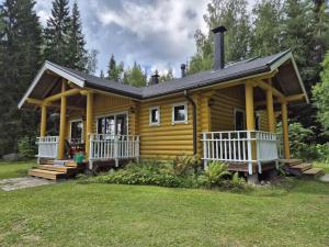 a small yellow cabin with a porch and a roof at Välituvan lomamökit in Punkaharju