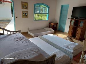 two beds in a room with a tv and a dog at Charmosa edícula próxima a praia in São Sebastião