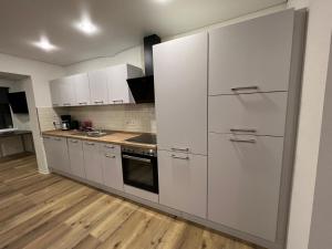 a kitchen with white cabinets and a wooden floor at Fewo An der Weser mit Sauna in Beverungen