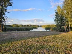 a picnic table in a field next to a lake at Sīvera Medniekkrasti in Stoli