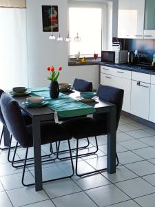 a dining room table with chairs and a kitchen at Ferienwohnung am Wald in Warstein