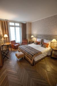 a hotel room with a large bed and tables and chairs at Villa Augeval Hôtel de charme & Spa in Deauville