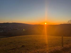 a sunset over a field with the sun setting at Ferienhaus MaLu in Nonnweiler