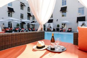 una botella de vino y un sombrero en una mesa junto a una piscina en Casa Monica Resort & Spa, Autograph Collection, en St. Augustine