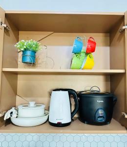 a cupboard with a coffee maker and pots and pans at ZK Homestay in Puerto Princesa City