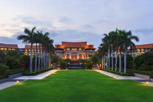 a building with palm trees in front of a lawn at Renaissance Sanya Haitang Bay Resort in Sanya