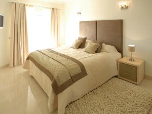 - une chambre blanche avec un grand lit et une fenêtre dans l'établissement Quinta da Floresta – Santo António Villas, Golf & Spa, à Budens