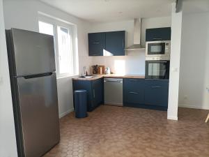 a kitchen with blue cabinets and a stainless steel refrigerator at Location des longères in Brux