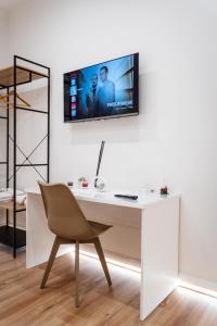 a white desk with a chair and a tv on a wall at Mar House & Suites Guest House in Castellammare di Stabia