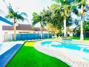 a swimming pool in a yard with palm trees at La Casa Villa in Richards Bay