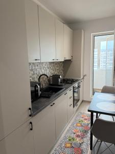a kitchen with white cabinets and a table and a window at RULU Studio Militari Residence Ballroom in Roşu