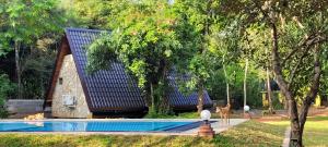 a house with a blue roof next to a swimming pool at Lion King Jungle Cabanas in Sigiriya