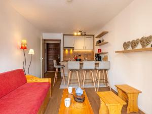 a living room with a red couch and a kitchen at Appartement rénové skis aux pieds avec parking couvert, au cœur de Val-d'Isère - FR-1-694-280 in Val dʼIsère