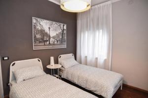 een slaapkamer met 2 bedden, een tafel en een kroonluchter bij L'Agrifoglio Affittacamere in Gattinara