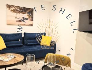 ヘルにあるWhite Shell Apartament Helのリビングルーム(青いソファ、テーブル2台付)