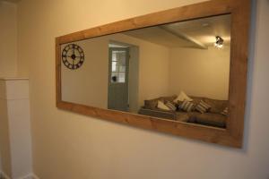 uno specchio su un muro con un divano in una stanza di White Swan Cottage 2 a Hunmanby
