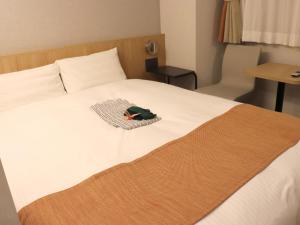 a white bed with a green bag on it at Tokyo Inn in Tokyo +79 photos