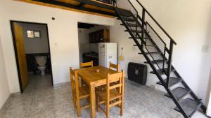 a dining room with a table and a spiral staircase at Duplex con patio y cochera, con aire acondicionado y vajilla completa en el centro de Choele Choel in Choele Choel