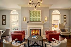 a living room with a fireplace and red chairs at Morrison House Old Town Alexandria, Autograph Collection in Alexandria