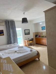 a bedroom with two beds and a kitchen with a table at Majki Beach Apartments in Sarandë