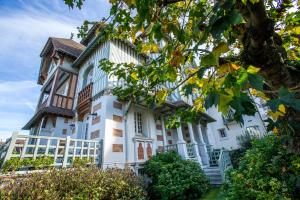 a large white building with a tree in the foreground at Villa Augeval Hôtel de charme & Spa in Deauville