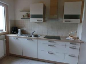 eine Küche mit weißen Schränken und einem Waschbecken in der Unterkunft Apartment Herbert Panter in Bad Peterstal-Griesbach