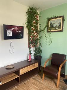 a living room with a table and a chair and a tv at Canto do Aconchego Praia de Itaparica in Vila Velha