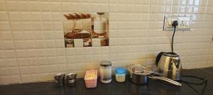 a counter top with a coffee maker and cups at Feel Home Stay in Urapakkam