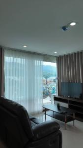 a living room with a couch and a table and a large window at Kashouse hatyai in Ban Khlong Pleo