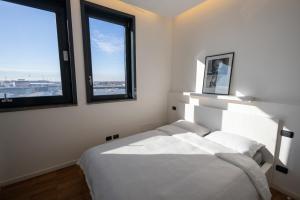 a bedroom with a white bed and two windows at Bianca Apartments in Verona
