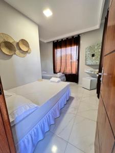a bedroom with a large bed and a window at Balanço do Mar - Suítes in Prado
