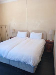 Cozy room in the Heart of Simon's Town في كيب تاون: سرير كبير بملاءات ووسائد بيضاء