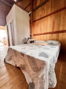 a bed in a room with a wooden wall at Hostel Capitão da Ilha in Algodoal