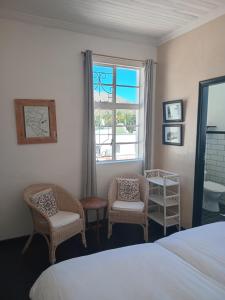 Cozy room in the Heart of Simon's Town في كيب تاون: غرفة نوم بسرير وكرسيين ونافذة