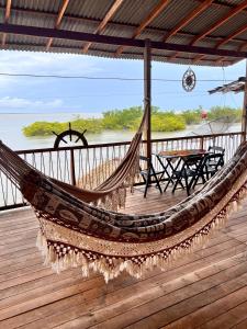 a hammock on top of a deck with a table at Hostel Capitão da Ilha in Algodoal